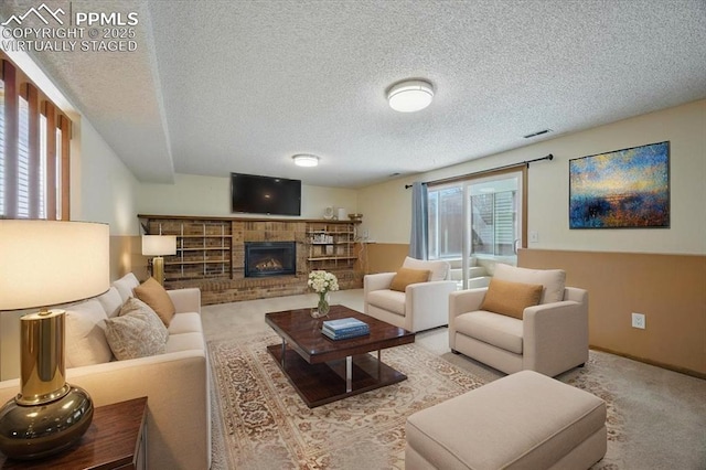 living room featuring carpet floors, a textured ceiling, visible vents, and a brick fireplace