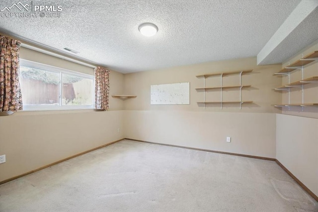carpeted spare room featuring baseboards, a textured ceiling, and visible vents