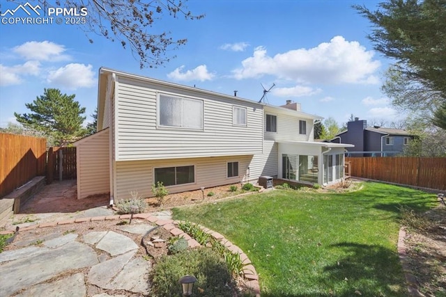 rear view of house with a yard, central AC unit, a fenced backyard, and a chimney