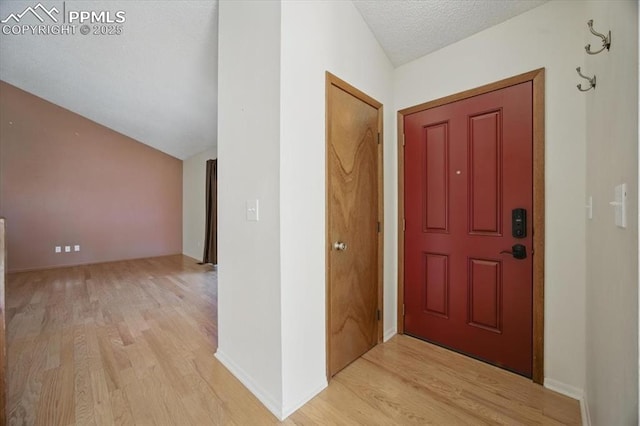 entryway featuring light wood-style floors, a textured ceiling, and baseboards