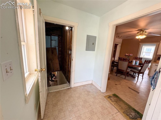 hall with electric panel, baseboards, and light floors