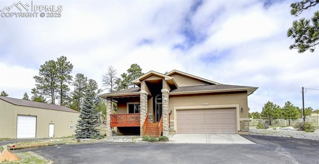 12590 Holmes Rd, Black Forest, CO 80908 - view of front of house with stone siding, a garage, aphalt driveway, stucco siding, and covered porch