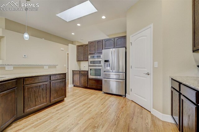 12590 Holmes Rd, Black Forest, CO 80908 - kitchen with pendant lighting, dark brown cabinetry, light wood-style flooring, appliances with stainless steel finishes, and a skylight