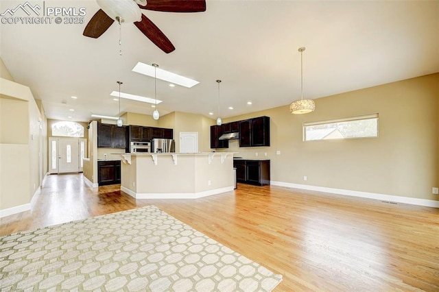 12590 Holmes Rd, Black Forest, CO 80908 - kitchen with light wood-style floors, open floor plan, a breakfast bar area, under cabinet range hood, and stainless steel appliances