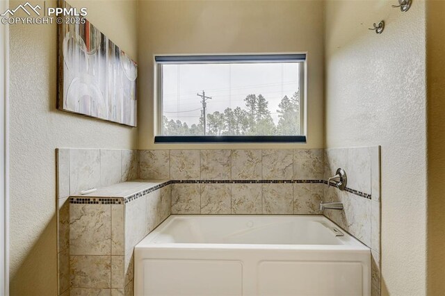 12590 Holmes Rd, Black Forest, CO 80908 - full bathroom with a healthy amount of sunlight, a textured wall, and a garden tub