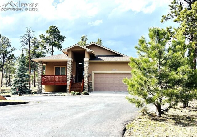 12590 Holmes Rd, Black Forest, CO 80908 - view of front facade with a garage, stucco siding, stone siding, and concrete driveway