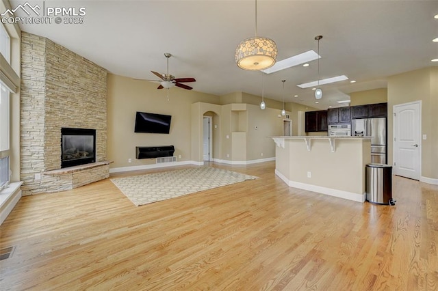 12590 Holmes Rd, Black Forest, CO 80908 - unfurnished living room featuring a stone fireplace, light wood finished floors, ceiling fan, and baseboards