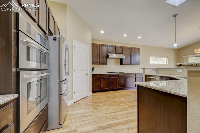 12590 Holmes Rd, Black Forest, CO 80908 - kitchen featuring pendant lighting, appliances with stainless steel finishes, light stone countertops, dark brown cabinets, and light wood-style floors