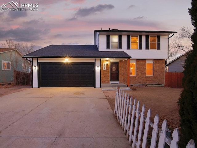 traditional-style home with a garage, brick siding, concrete driveway, and fence