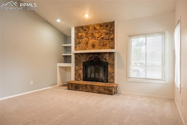 unfurnished living room featuring baseboards, a fireplace, carpet flooring, and lofted ceiling