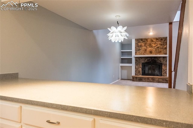 unfurnished living room with an inviting chandelier, built in features, and a stone fireplace