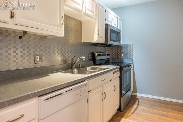 kitchen featuring a sink, decorative backsplash, appliances with stainless steel finishes, and white cabinetry