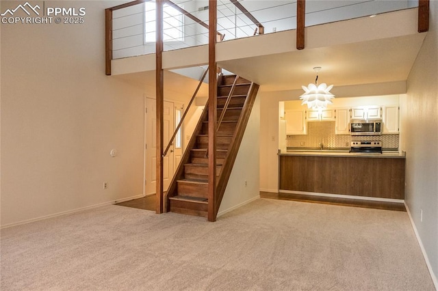 interior space with carpet floors, baseboards, stairs, and a towering ceiling