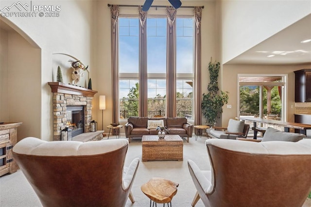 living room with light carpet, a stone fireplace, and a towering ceiling