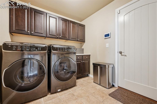 washroom with light tile patterned flooring, separate washer and dryer, cabinet space, and baseboards