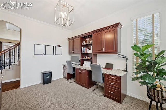 office area featuring baseboards, ornamental molding, light colored carpet, and built in desk