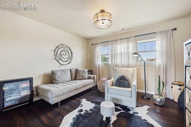 living room featuring wood finished floors, visible vents, and baseboards