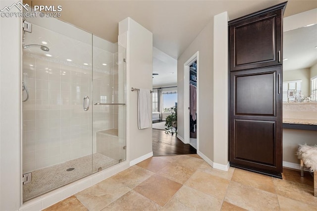 bathroom featuring a stall shower, baseboards, and plenty of natural light