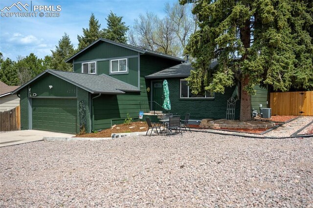 tri-level home with fence, roof with shingles, concrete driveway, and central air condition unit