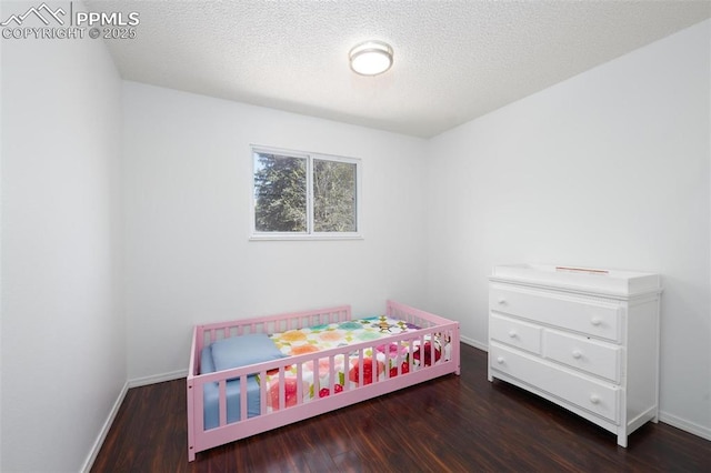 bedroom featuring a textured ceiling, wood finished floors, and baseboards