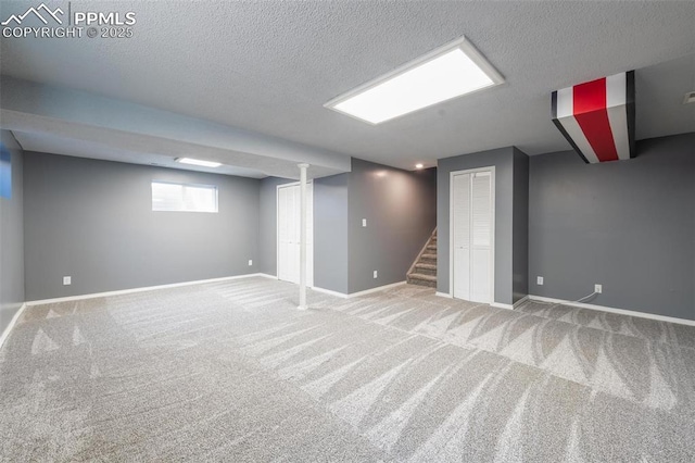 below grade area with a textured ceiling, carpet flooring, stairway, and baseboards