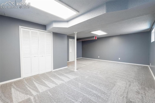 finished below grade area featuring carpet, baseboards, and a textured ceiling