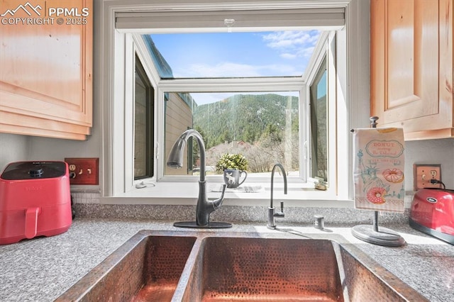 interior details with light brown cabinetry, a sink, and light countertops