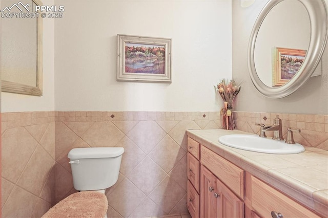 half bathroom with tile walls, toilet, and vanity