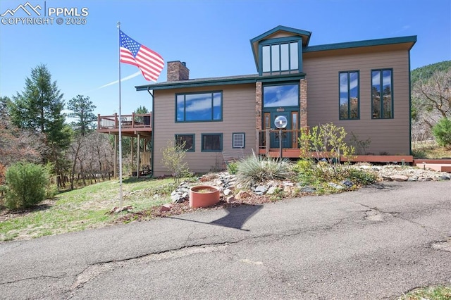 view of front of house featuring a chimney and a deck