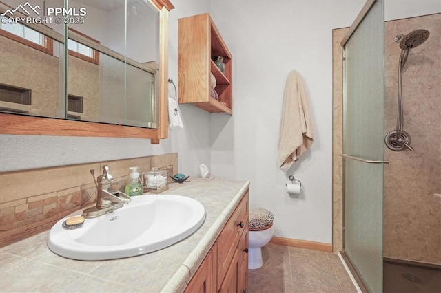 bathroom with a shower stall, toilet, vanity, and baseboards