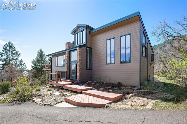 back of property featuring a chimney, central air condition unit, and a deck