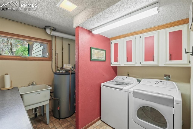 washroom featuring a textured ceiling, a sink, washer and clothes dryer, gas water heater, and cabinet space