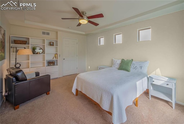 carpeted bedroom featuring a raised ceiling, visible vents, and ceiling fan