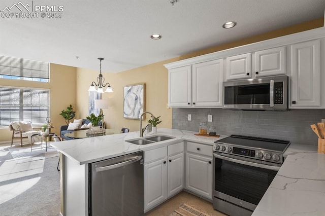 kitchen with a sink, decorative backsplash, white cabinets, a peninsula, and appliances with stainless steel finishes