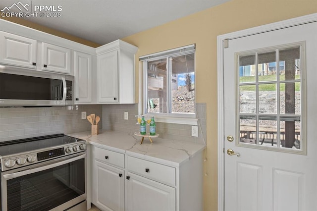 kitchen featuring backsplash, appliances with stainless steel finishes, light stone counters, and white cabinets