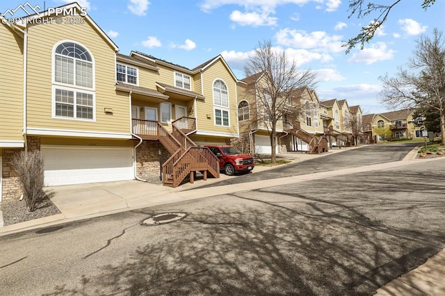 view of front facade with a residential view, an attached garage, concrete driveway, and stairway