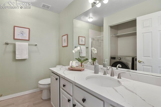 full bathroom with a shower stall, wood finished floors, visible vents, vanity, and washer / dryer