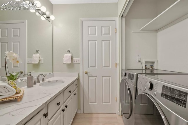 washroom with washing machine and clothes dryer, light wood finished floors, a sink, and laundry area