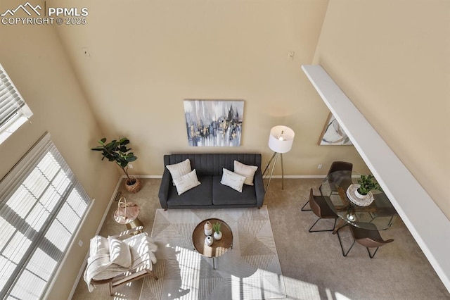 carpeted living room featuring baseboards and a towering ceiling