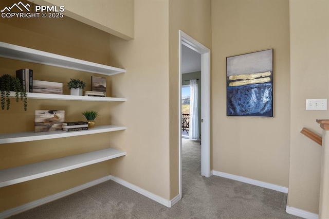 corridor featuring baseboards and carpet flooring