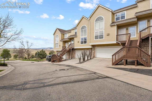 view of front of home with concrete driveway, stairway, a mountain view, and a garage