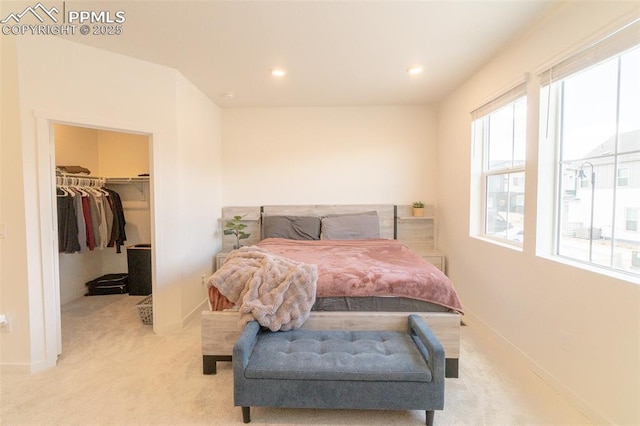 bedroom with recessed lighting, a spacious closet, baseboards, and light carpet