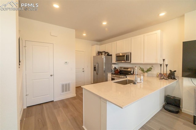 kitchen with a sink, visible vents, white cabinetry, light wood-style floors, and appliances with stainless steel finishes
