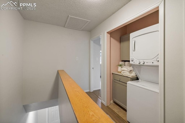 983 Moorings Dr, Colorado Springs, CO 80906 - laundry room featuring wood finished floors, a textured ceiling, attic access, stacked washer / drying machine, and laundry area
