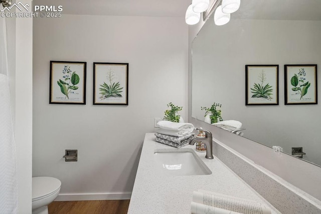 983 Moorings Dr, Colorado Springs, CO 80906 - full bathroom featuring wood finished floors, vanity, a chandelier, baseboards, and toilet