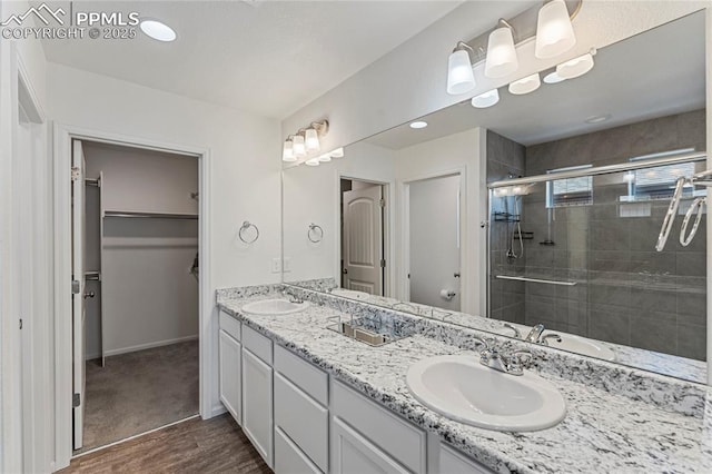 6117 Ashmore Ln, Colorado Springs, CO 80927 - full bathroom featuring double vanity, wood finished floors, a stall shower, and a sink