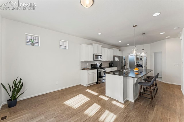 6117 Ashmore Ln, Colorado Springs, CO 80927 - kitchen with a breakfast bar area, a sink, appliances with stainless steel finishes, dark countertops, and a kitchen island with sink