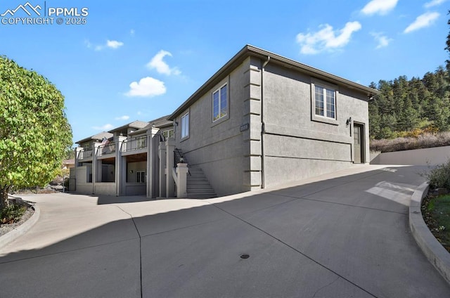 back of house featuring stairway and driveway