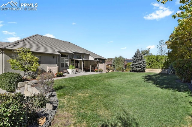 back of house featuring fence, a tile roof, stucco siding, a sunroom, and a yard
