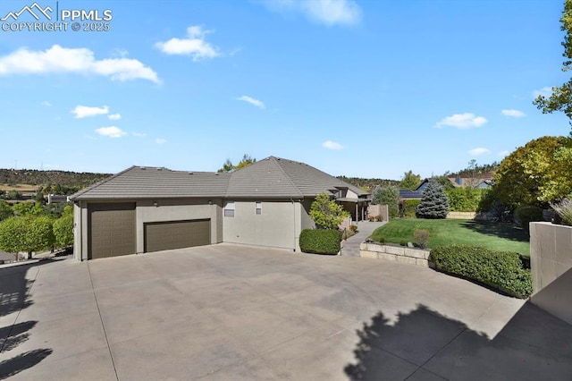 view of front facade with driveway, a tile roof, a front lawn, an attached garage, and stucco siding